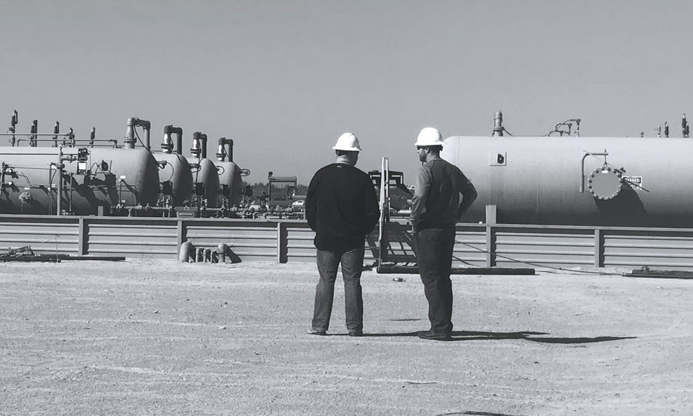 Two men in hardhats at an oil facility