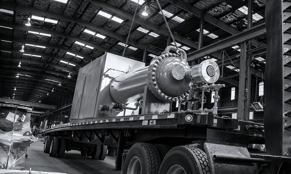 Flat bed semi truck being loaded with heavy equipment